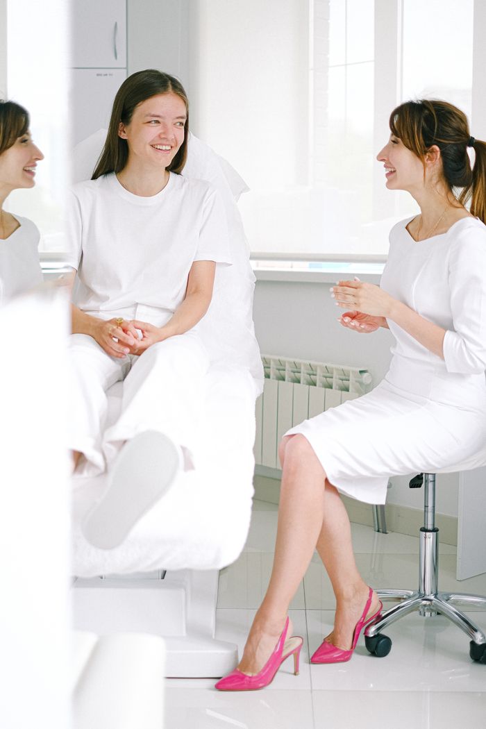 Two women happily conversing in a bright and modern medical clinic.